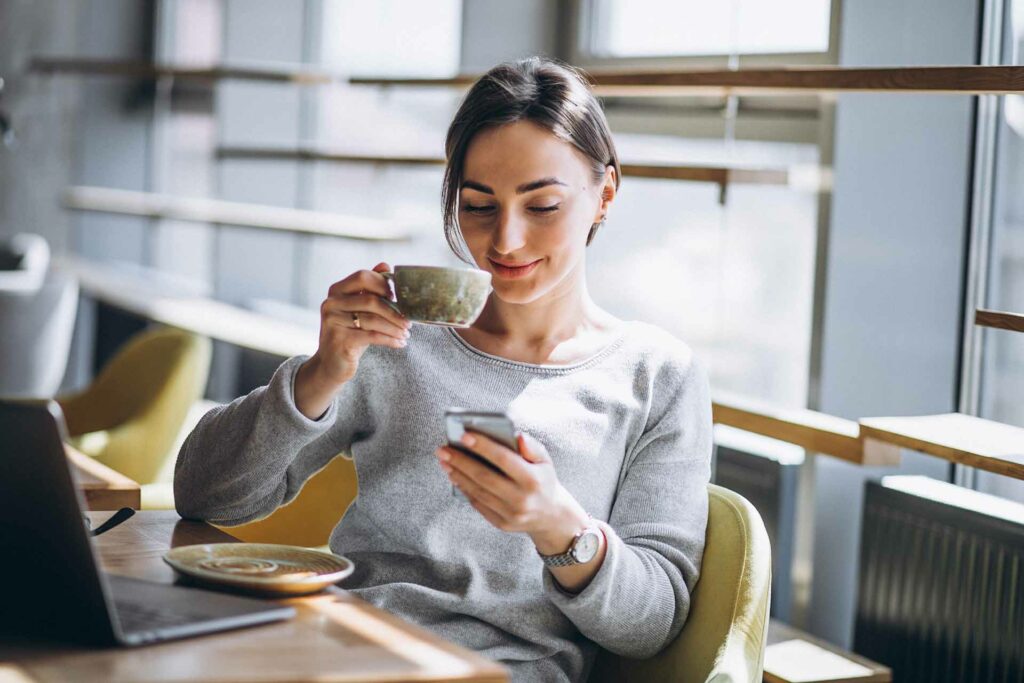 Frau trinkt Kaffee und schaut auf die Baufi-App
