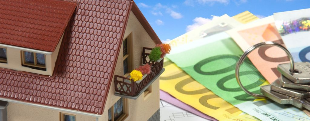 Bauzins: Haus auf Geldscheinen mit Schlüsseln mit Wolken im Hintergrund