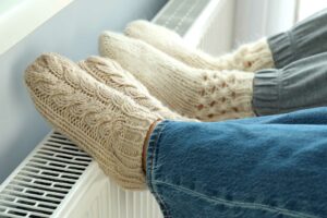 Heizung: Füße wärmen sich an einem Heizkörper