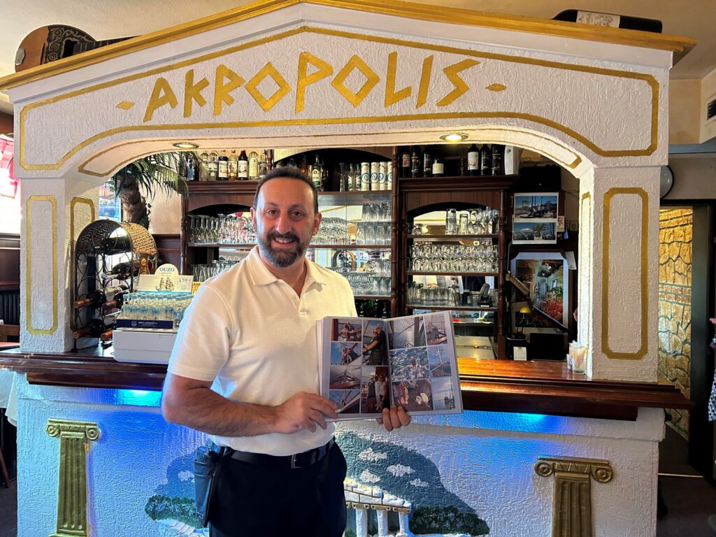 Restaurants in Schwachhausen: Christos vom Akropolis hält ein Reisebuch in der Hand