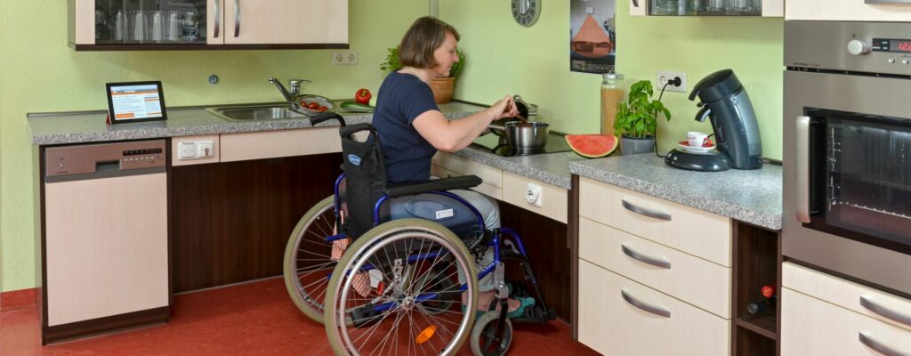 Barrierefreies Wohnen: Rollstuhlfahrerin in einer behindertengerechten Küche