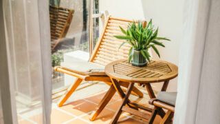 Bodenbelag Balkon: Gefliester Balkon mit Holzgartenmöbeln im Sonnenlicht