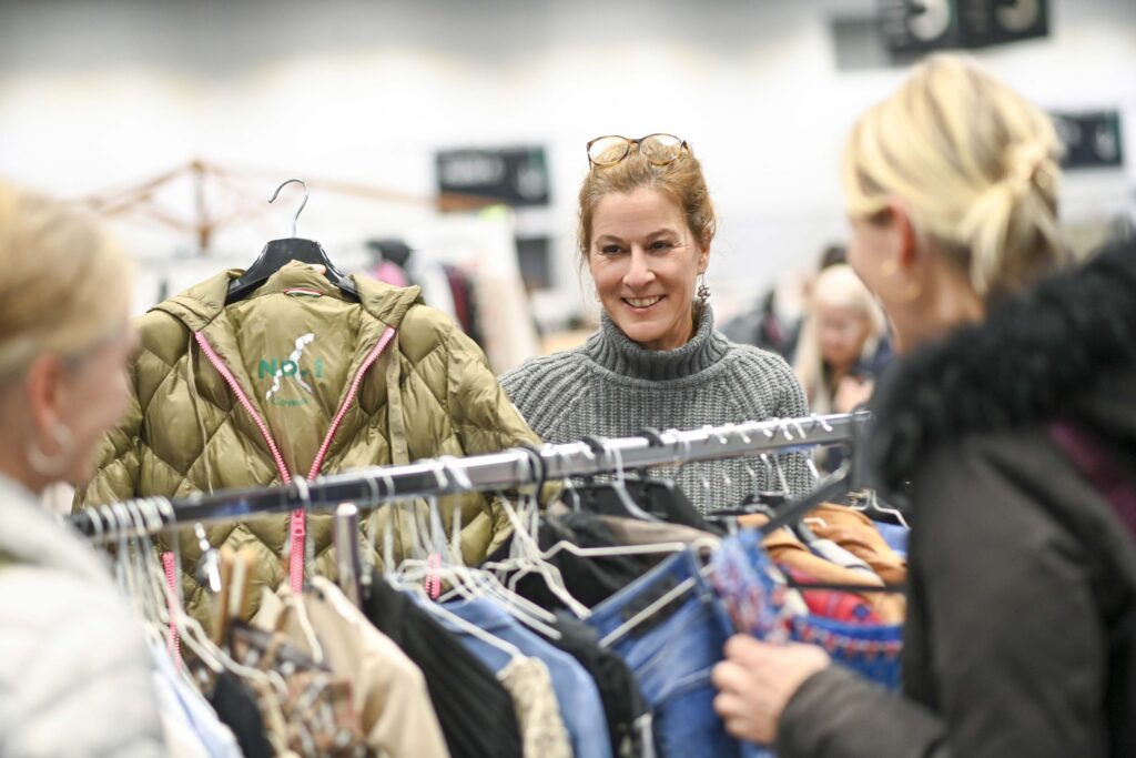 Mehrere Frauen stöbern an Kleiderständern auf dem Woman-Modeflohmarkt in Bremen