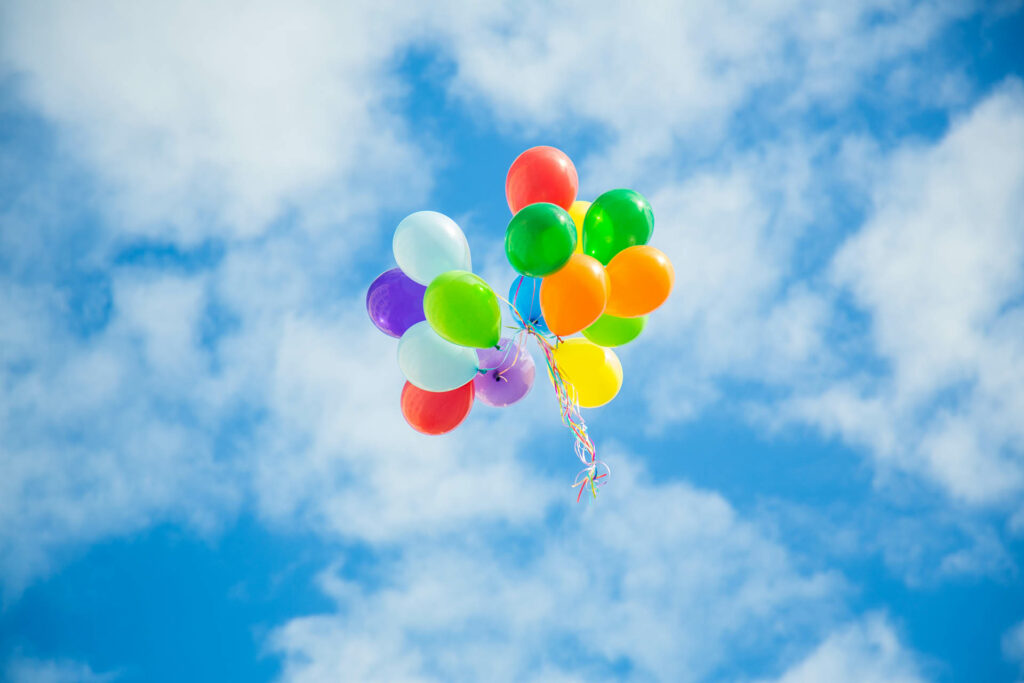 Luftballons schweben im Himmel vor Wolken