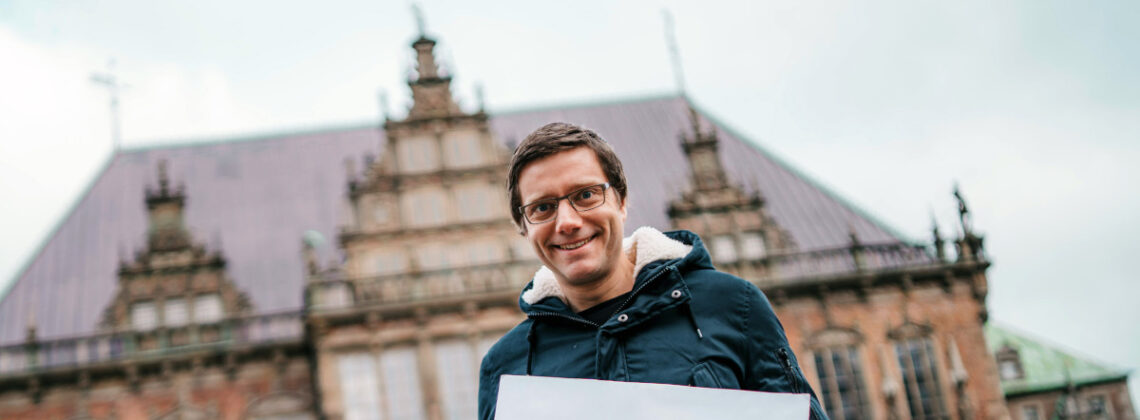 Mario Neumann hält ein Schild mit der Aufschrift "Eine Stunde reden?"