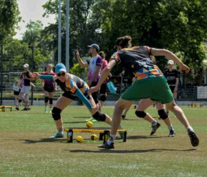 Angestrengte Sportlerinnen und Sportler schlagen beim Trendsport Roundnet einen kleinen Ball auf ein rundes Netz.