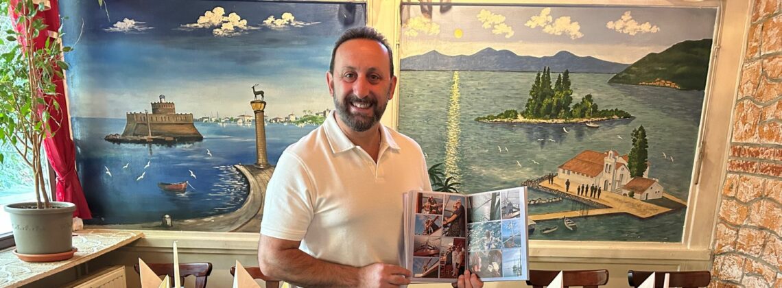 Christos Kalogirou vom Restaurant Akropolis in Bremen-Schwachhausen. Er hält ein Fotobuch in den Händen