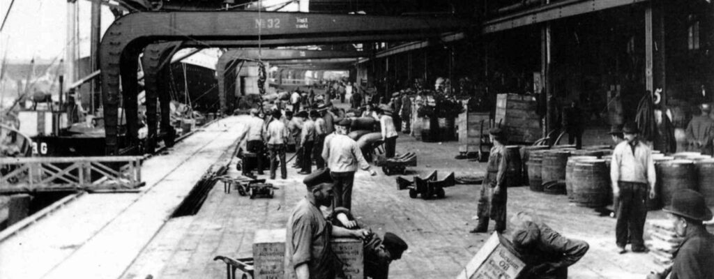 Hafenarbeiter mit Fracht auf Sackkarren im Hamburger Hafen um 1900