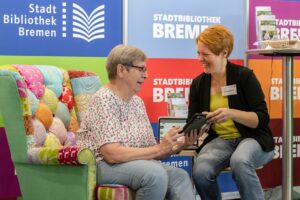 Eine Frau von der Stadtbibliothek Bremen berät eine Seniorin auf der Messe Invita darüber, wie eBooks verwendet werden