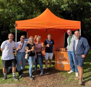 Vorstandsmitglieder halten Becher mit selbst gemachtem Popcorn am Infostand in die Höhe