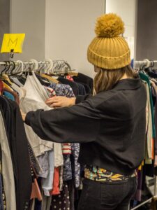 Junge Frau stöbert durch Kleidungsstücke bei der Kleidertauschbörse der Klimazone Findorff