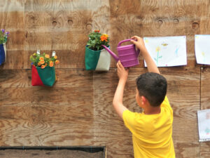 Ein Kind gießt Pflanzen eines vertikalen Gartens