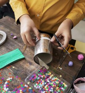 Person beim Upcycling mit einer leeren Dose und Bastelmaterial