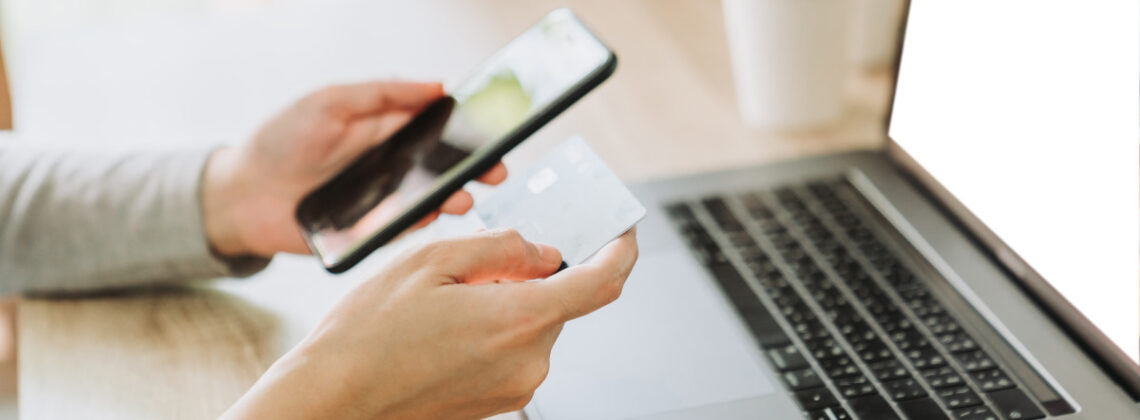 Mensch hält ein Smartphone und eine Chipkarte vor einen Laptop