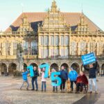 Verein für Innere Mission Bremen– Mitglieder posieren vor dem Bremer Rathaus mit den übergroßen blauen Zahlen 175 in den Händen