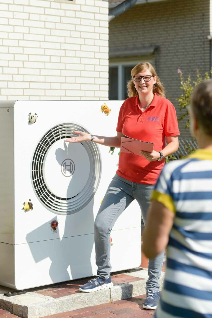 Energieberaterin steht vor einer Wärmepumpe