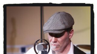 Mann mit Mütze ,Gitarre und Mikrofone