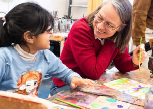 Senatorin für Kinder und Bildung, Sascha Karolin Aulepp malt zusammen mit einem Kind aus dem Startchancen-Projekt ein Bild