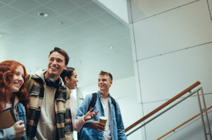 Vier junge Studierenden laufen in einer Uni die Treppe hoch