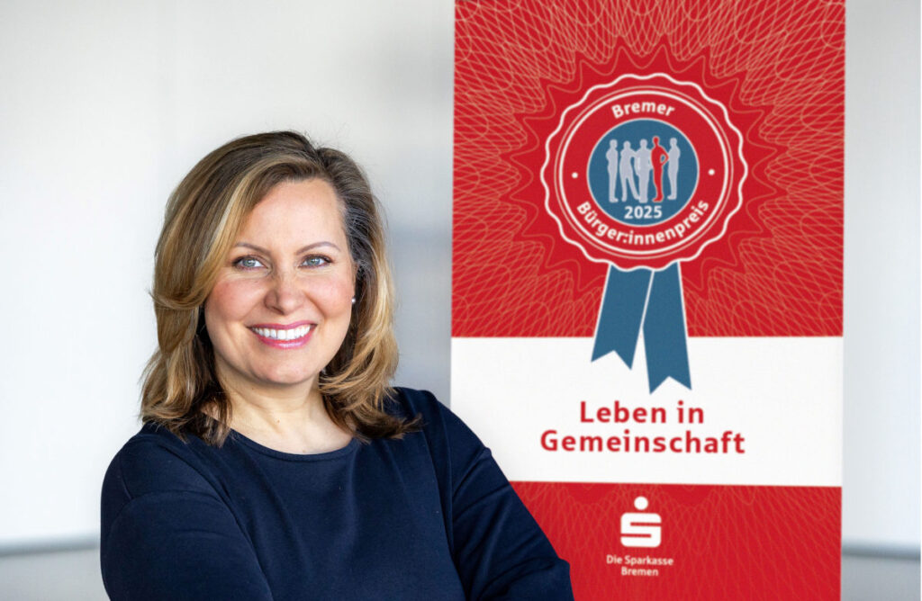 Bild von Sonja Kastin der Sparkasse Bremen vor einem Aufsteller des Bürger:innenpreis 2025
