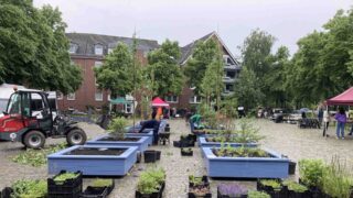 Mehrere blaue Hochbeete werden mit Pflanzen begrünt, begleitet von Anwohnenden und Helfenden beim Pop-up-Grün in Bremen-Gröpelingen