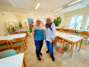 Leiterin Joyce Krijger (r.) und Kirsten Schnaars stehen im Saal des Begegnungszentrums Grambke und lächeln. 