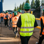 Menschen in Warnweste und Bauarbeiterhelmen laufen über einen Platz bei der Langen Nacht der Industrie
