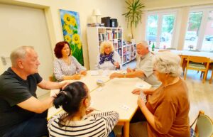 Mehrere Menschen sitzen an einem Tisch und spielen Karten beim Spieletreff im Begegnungszentrum Grambke. 