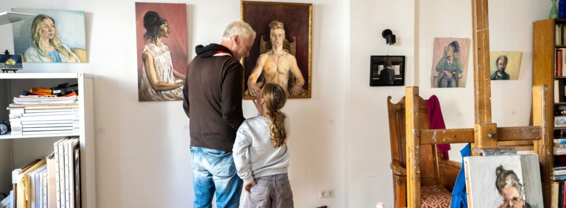 KunstWerk im Viertel: Ein Vater steht mit seiner Tochter in einem Atelier und begutachtet Malerei