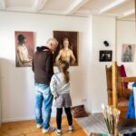 KunstWerk im Viertel: Ein Vater steht mit seiner Tochter in einem Atelier und begutachtet Malerei
