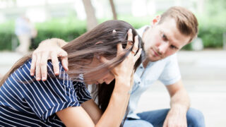 Eine junge Frau wird von einem jungen Mann würdevoll getröstet