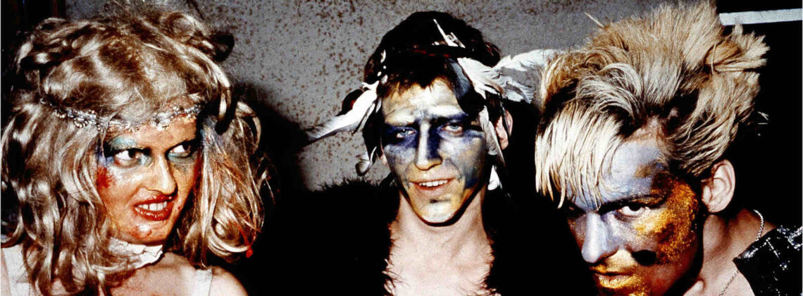 Drei wild gekleidete und geschminkte Menschen des Künstler*innenkollektivs "Die Tödliche Doris"