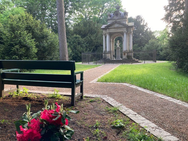 Parkanlage mit einer Bank, Blumen, Blumen, Büschen und Denkmal