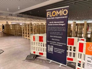 Blick auf die leeren Regale im Galeria Kaufhof Bremen und ein Schild vom Flomio-Flohmarkt.