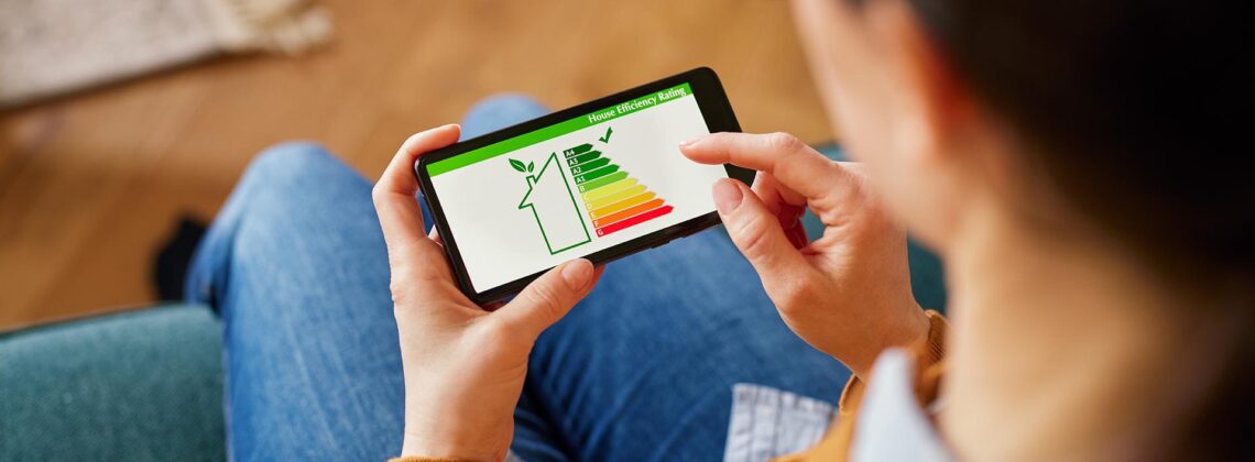 Person nutzt Smartphone mit Anzeige zur Energieeffizienz eines Hauses – Symbol für digitale Planung und nachhaltige Modernisierung
