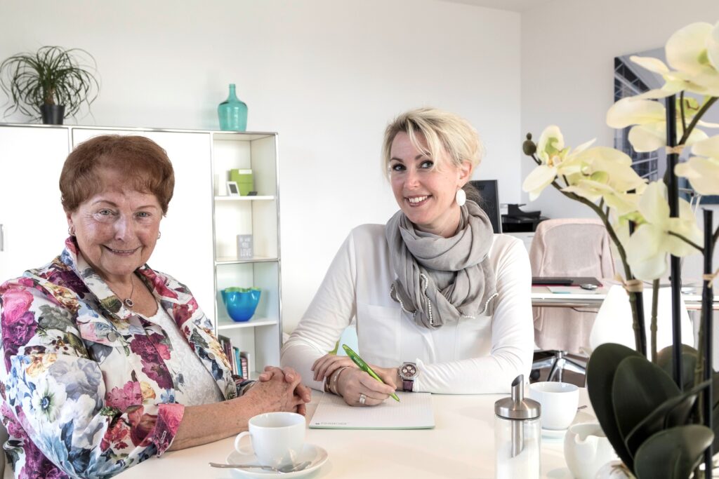 Zwei Damen die in die Kamera lächeln.