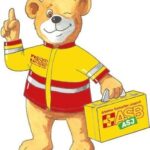 Ein Bär mit einer rot-gelben Rettungsjacke und einem Arztkoffer n der Hand
