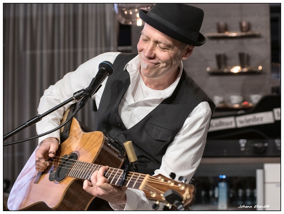 Ein Mann der auf seiner Gitarre spielt