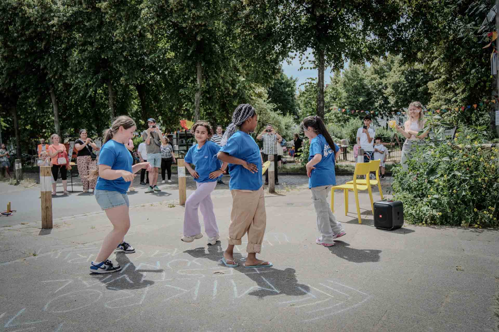Vier Mädchen der Tanzgruppe Backstage Girls tanzen bei einem Auftritt im Freien, umgeben von Zuschauerinnen und Zuschauern im Liegnitzquartier