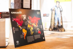 Informationstafel mit Weltkarte, die Klimawandelfolgen und betroffene Regionen visualisiert.