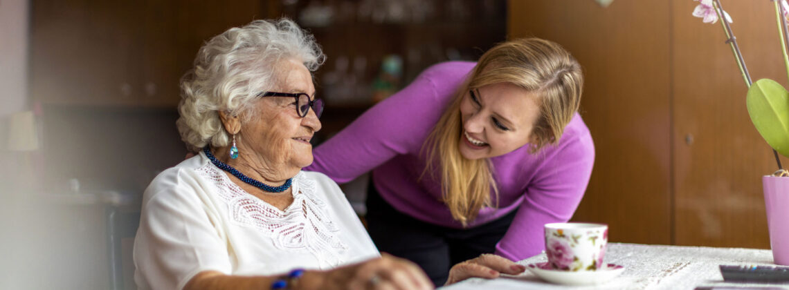 Senioren spricht mit einer jüngeren Frau, sie schauen sich in die Augen und lächeln. Symbolbild für Marte Meo Bremen
