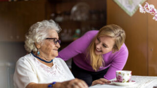 Senioren spricht mit einer jüngeren Frau, sie schauen sich in die Augen und lächeln. Symbolbild für Marte Meo Bremen