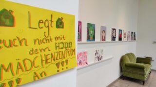 Teilnehmende gestalten in einem Kreativworkshop ein Kunstprojekt mit Farben und Pinseln