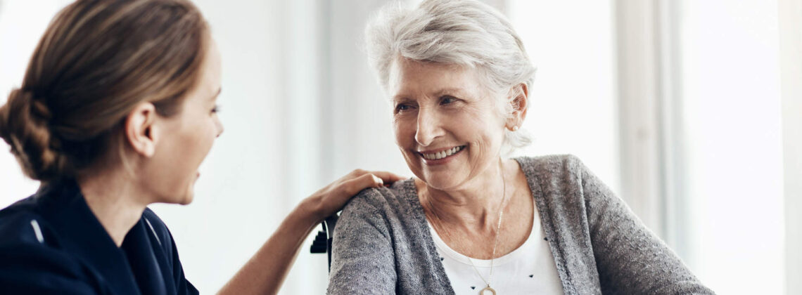 Eine Pflegerin legt einer Senioren die Hand auf die Schulter. Die Seniorin lächelt. Symbolbild für Pflegeversicherung Bremen Beratung