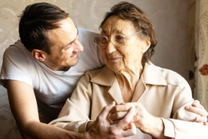 Ein Mann lächelt einer Senioren zu und umarmt sie. Symbolbild für pflegende Angehörige in Bremen