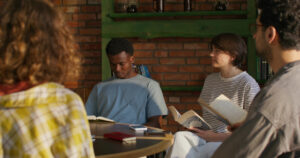 Junge Menschen sitzen zusammen an einem Tisch und lesen in Büchern, Symbolbild für Silent Reading