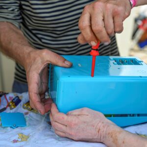 Nahaufnahme eines blauen Gegenstands, der mit einem roten Schraubendreher repariert wird 