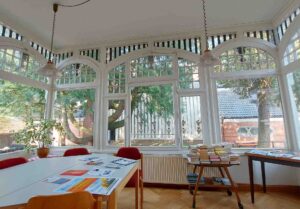 Der Wintergarten der Hackfeldschen Villa mit verzierten Fenstern und Büchertischen