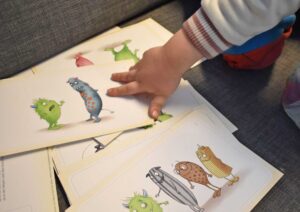 Kind betrachtet Bildkarten mit Figuren, die in den Übungen helfen, Gefühle wahrzunehmen und zu benennen.