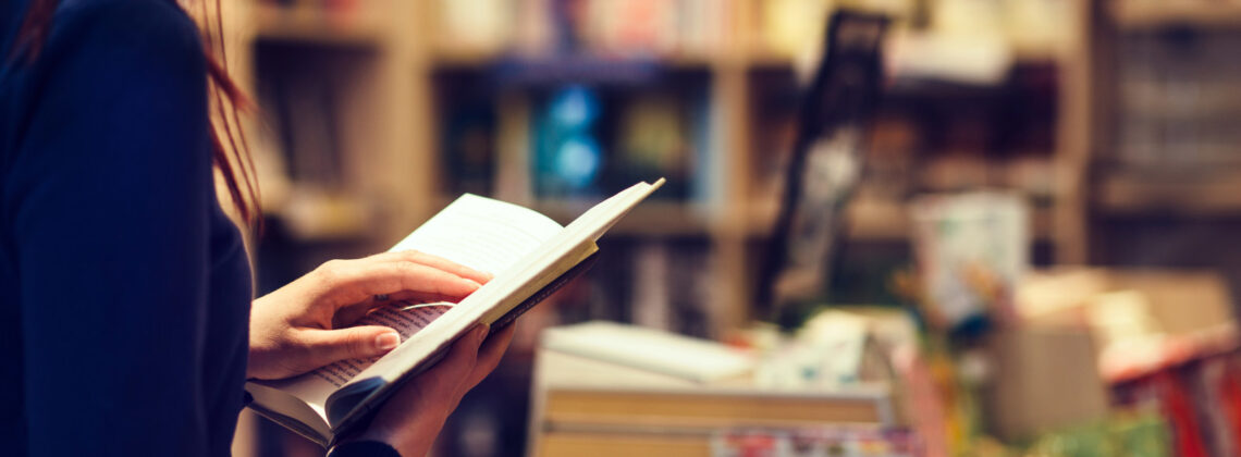 Eine Frau hält in einem Buchladen ein offenes Buch in den Händen und liest darin, Symbolbild für Lesung im Kulturraum Horn-Lehe